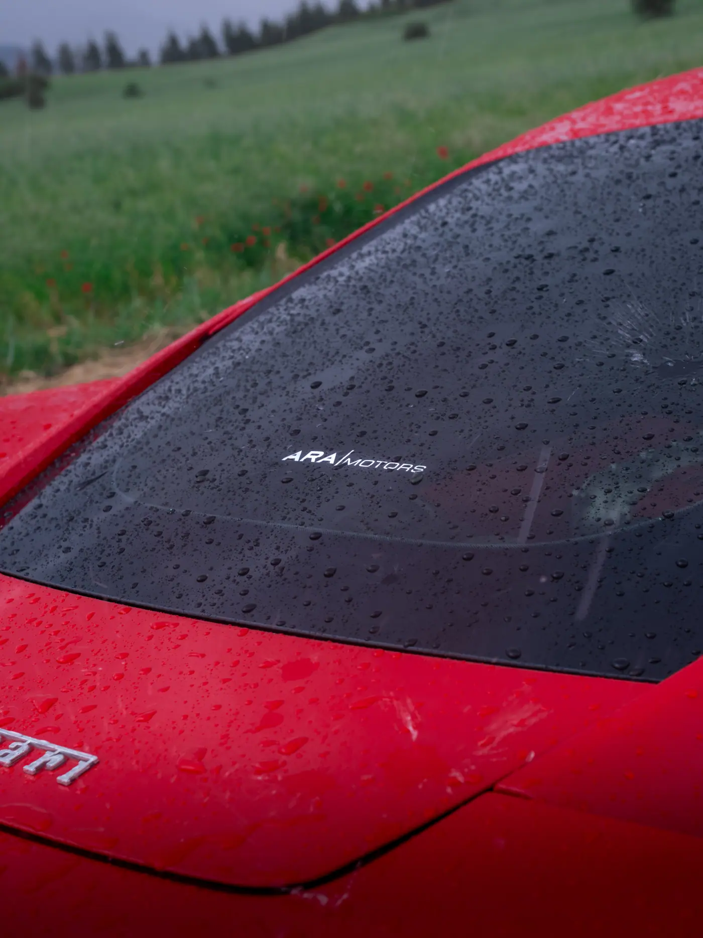 Ara Motors logosu ve yağmur damlalarıyla Ferrari cam detayı